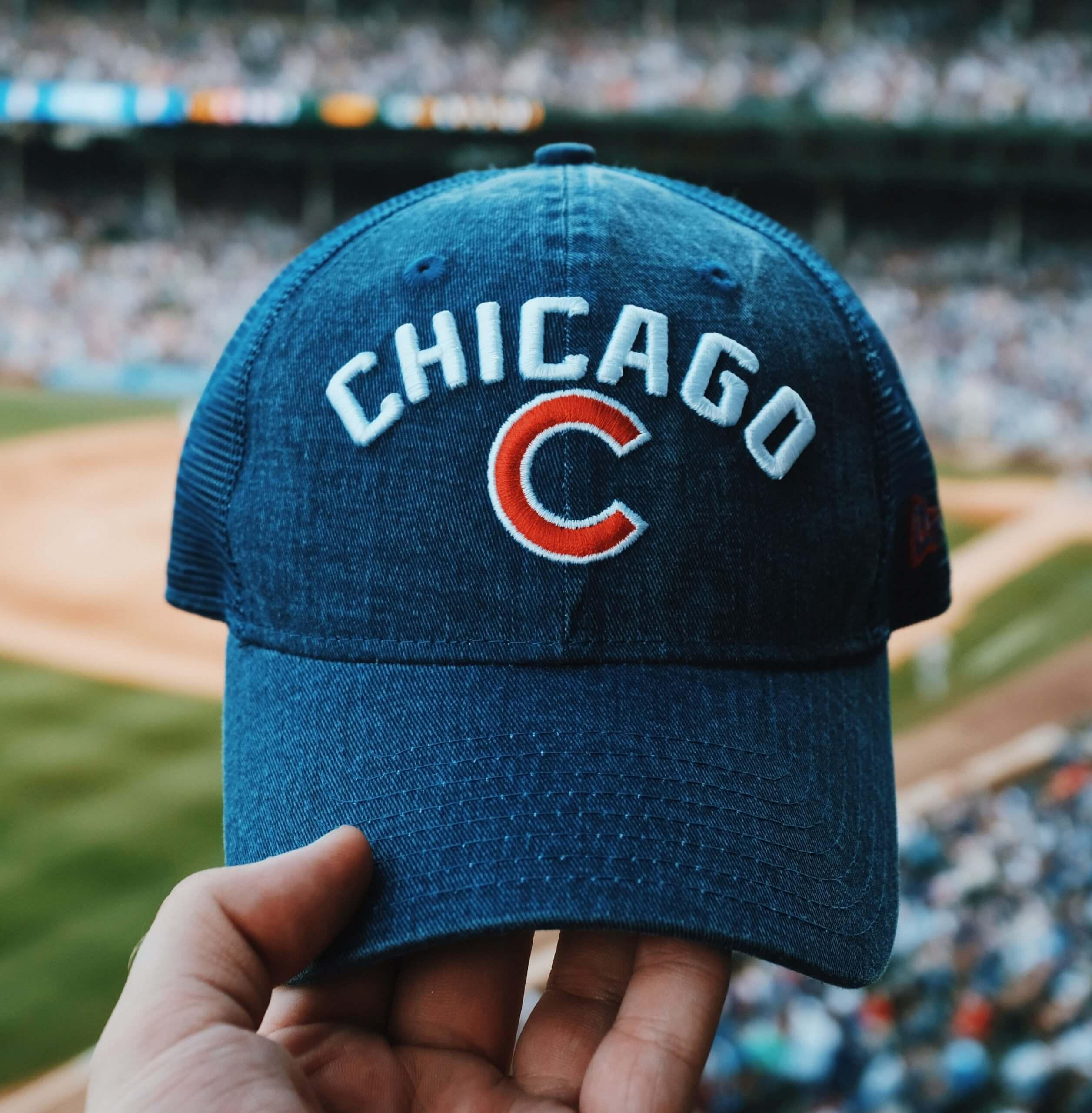 Person holding a Chicago cubs hat in front of Wrigley Field